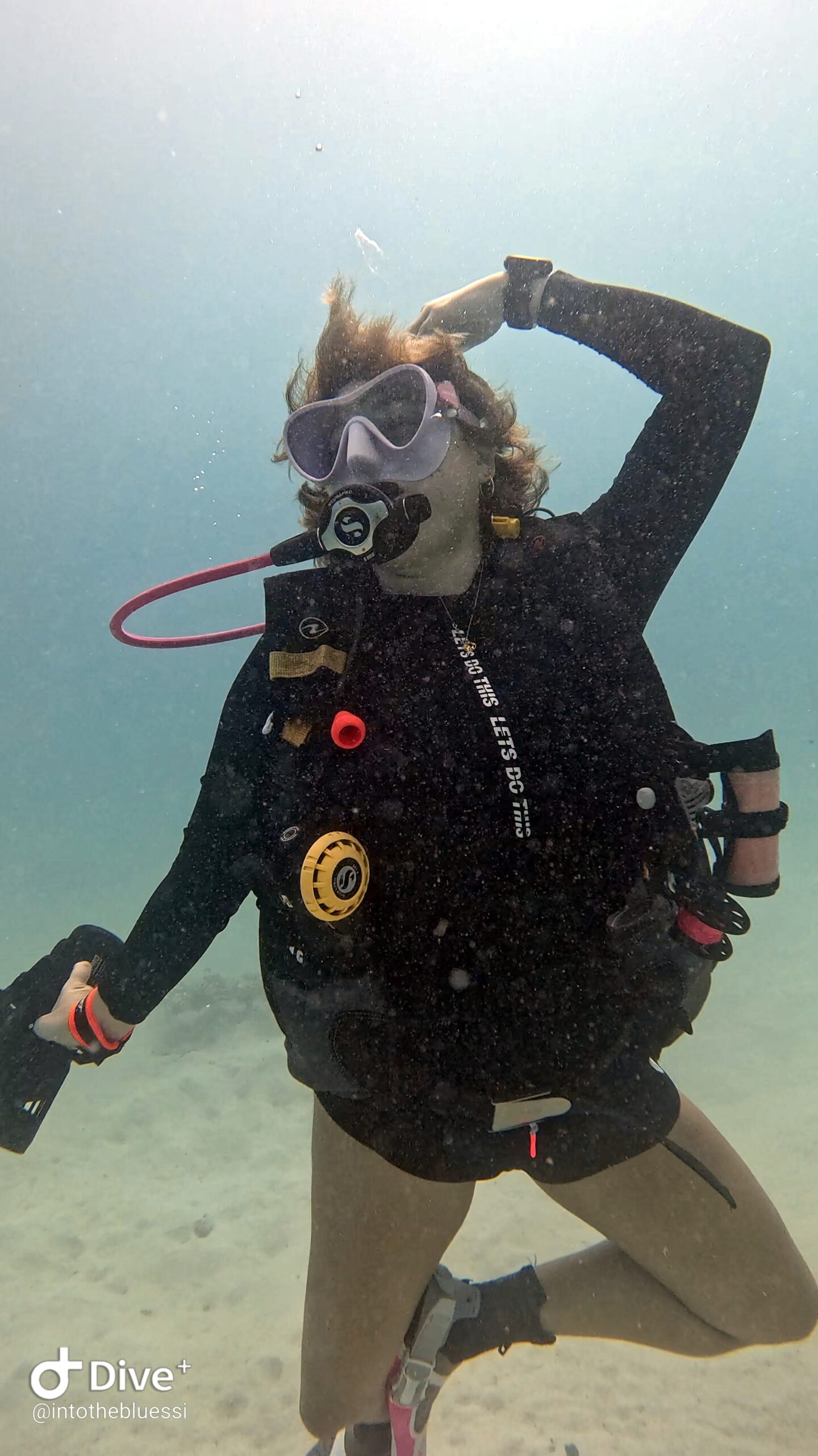 Scuba diver doing a playful ballet pose underwater while holding a DPV (Diver Propulsion Vehicle) during a specialty dive in Koh Tao, Thailand.