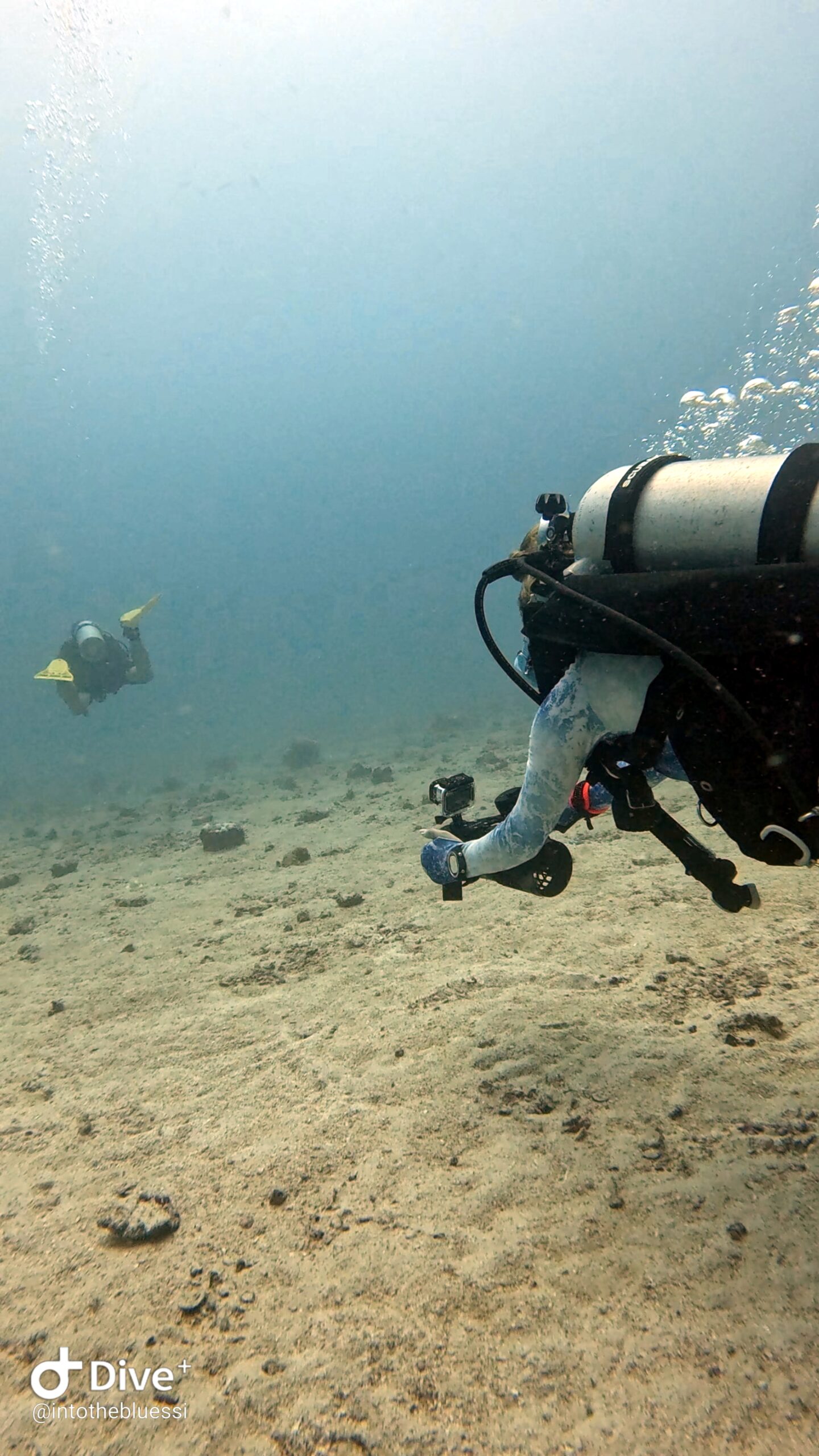 Two scuba divers practicing buddy coordination and navigation techniques with DPVs (underwater scooters) during a specialty dive in Koh Tao, Thailand.