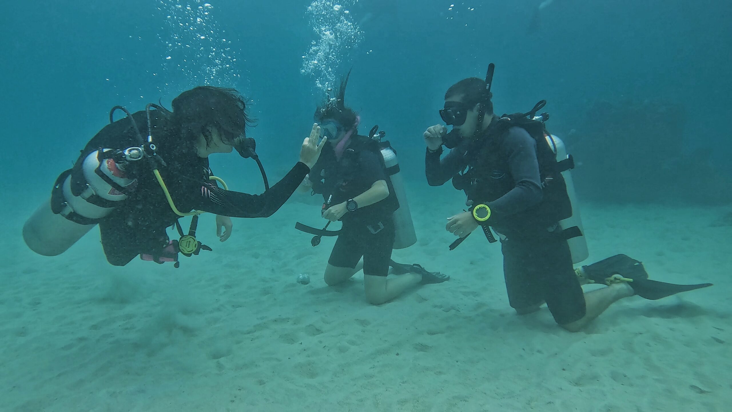 Scuba diving instructor teaching two beginner students underwater during a skills session – personalized Open Water course training at Dive In Koh Tao.