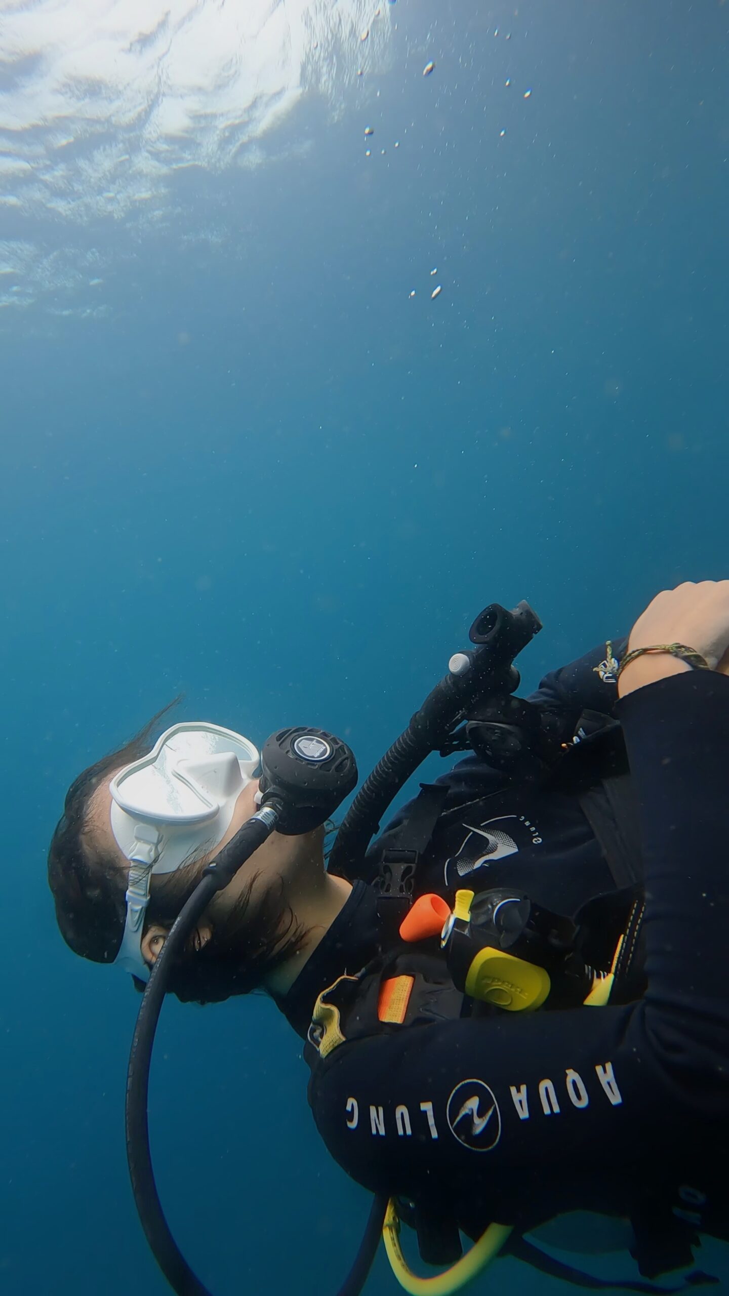 Scuba diving student ascending in clear blue water during open water training with Dive In Koh Tao