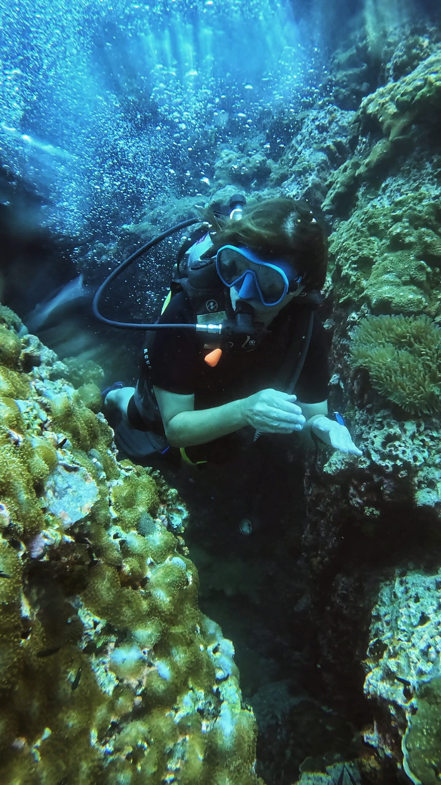 Scuba diver navigating a coral swim-through while practicing underwater navigation skills during Advanced Adventurer course at Dive In Koh Tao.