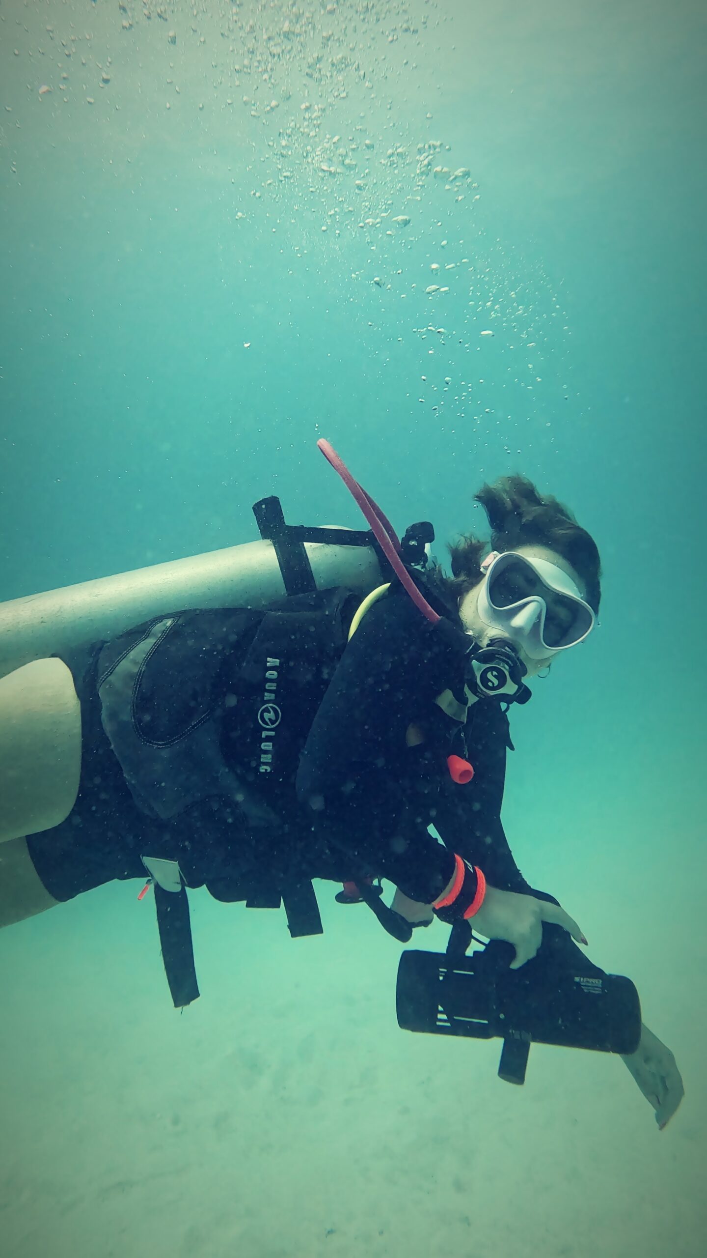 Scuba diver holding and steering a DPV underwater scooter while practicing control techniques during a specialty dive course in Koh Tao, Thailand.