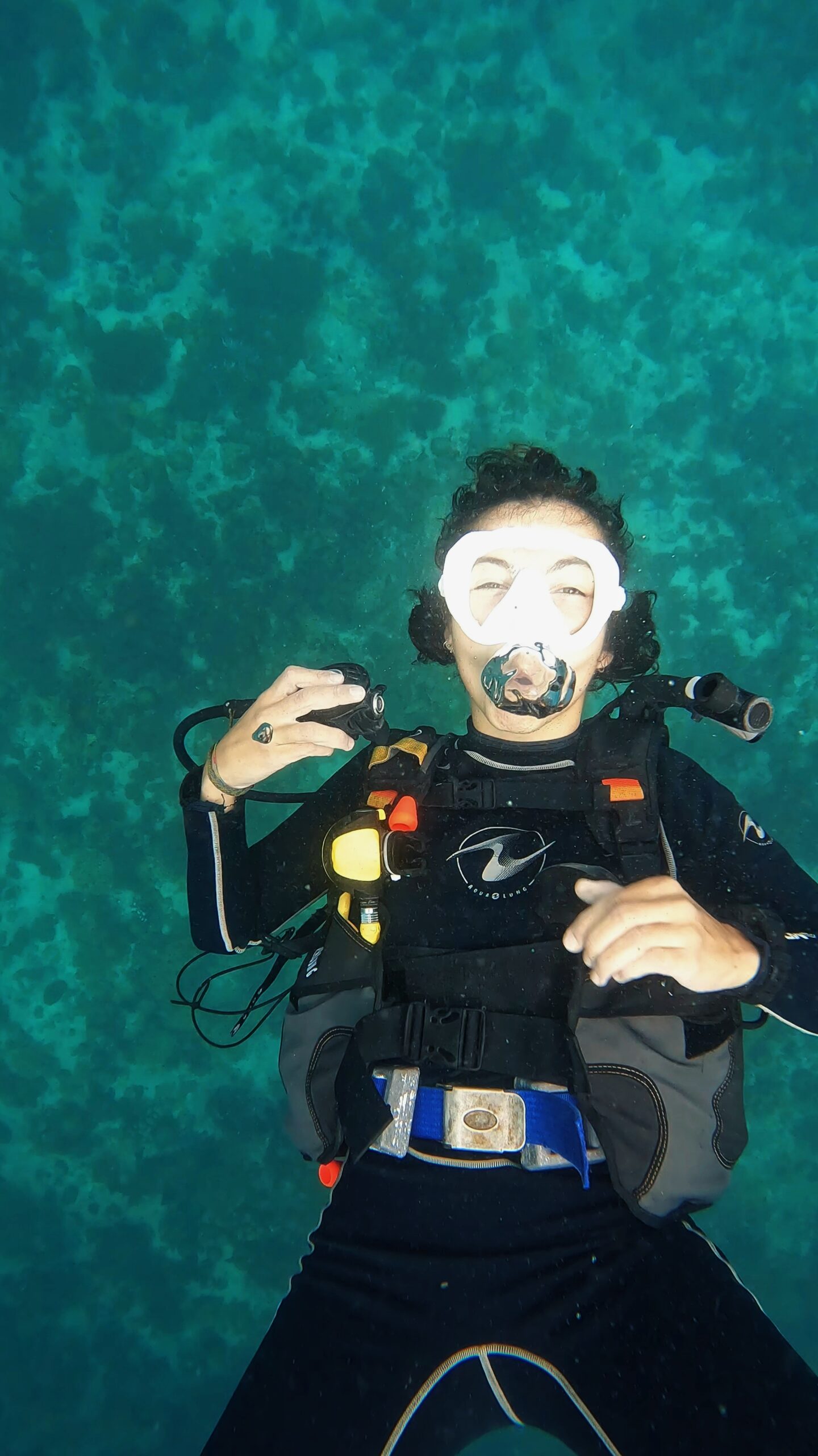 Scuba diver floating calmly above a shallow coral reef, practicing buoyancy and breath control during a dive training session in Koh Tao.