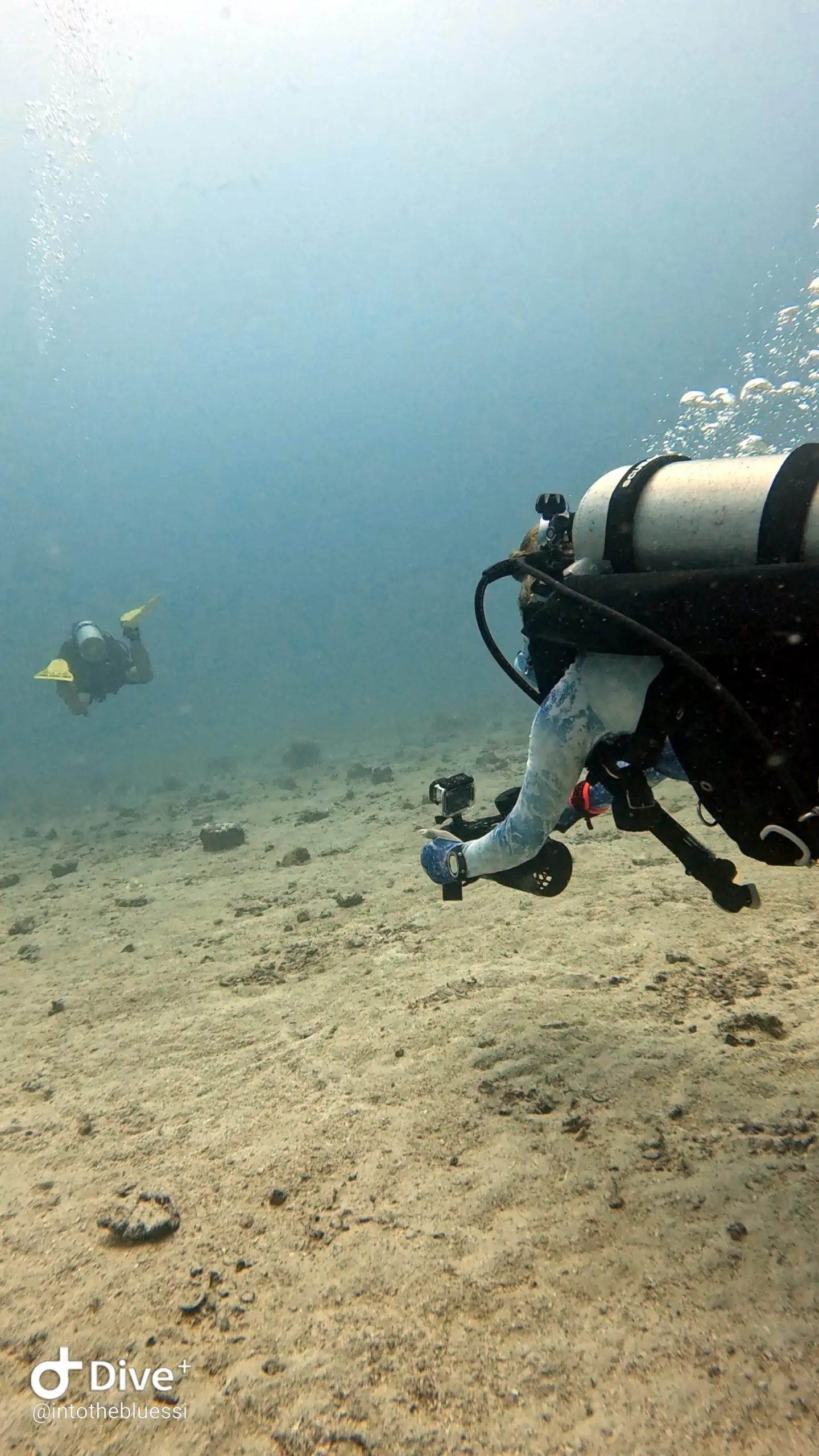 Two scuba divers practicing buddy coordination and navigation techniques with DPVs (underwater scooters) during a specialty dive in Koh Tao, Thailand.
