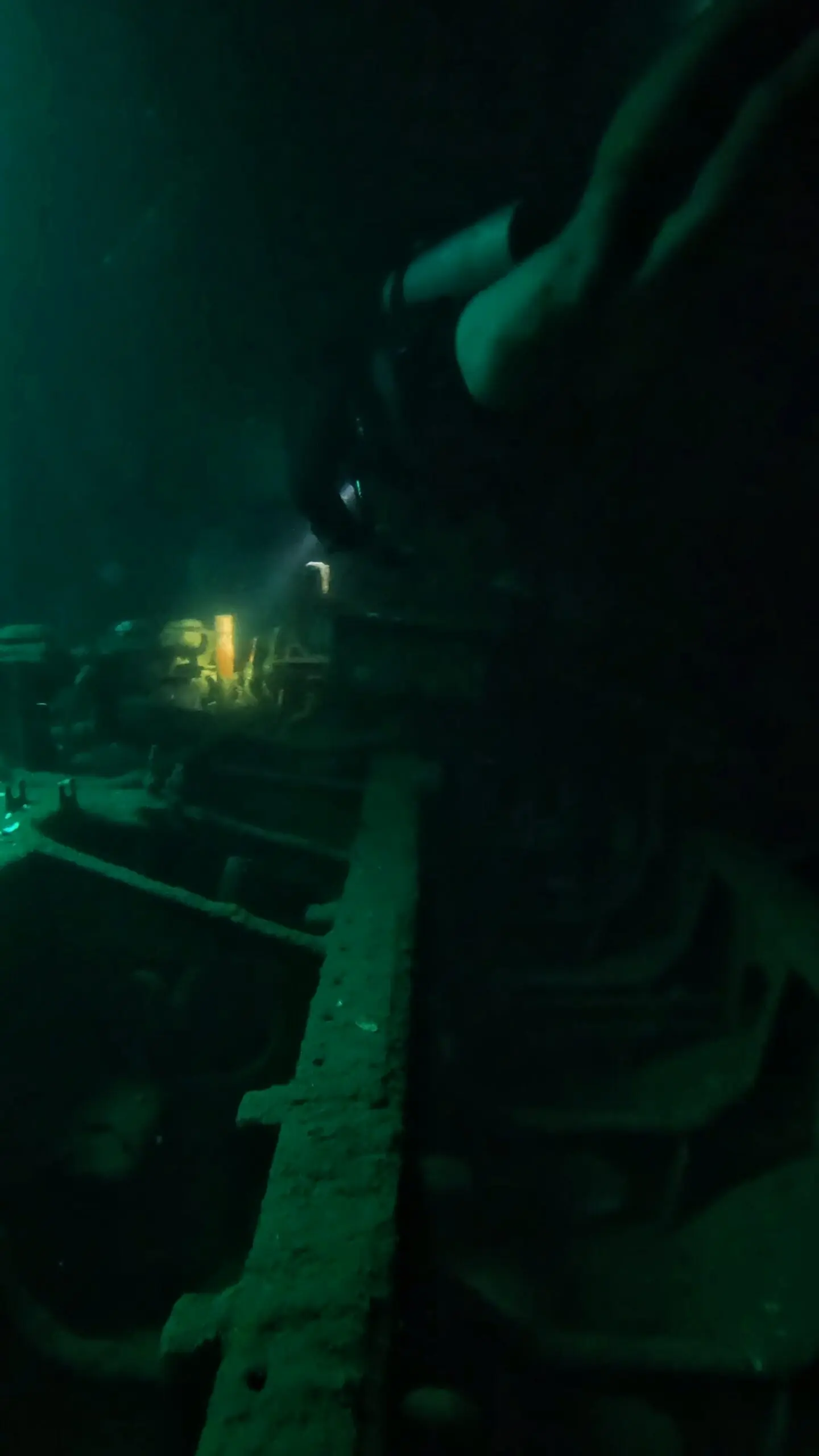 Scuba diver penetrating the interior of the Sattakut 742 wreck near No Name Pinnacle in Koh Tao, exploring the ship’s compartments with a flashlight.