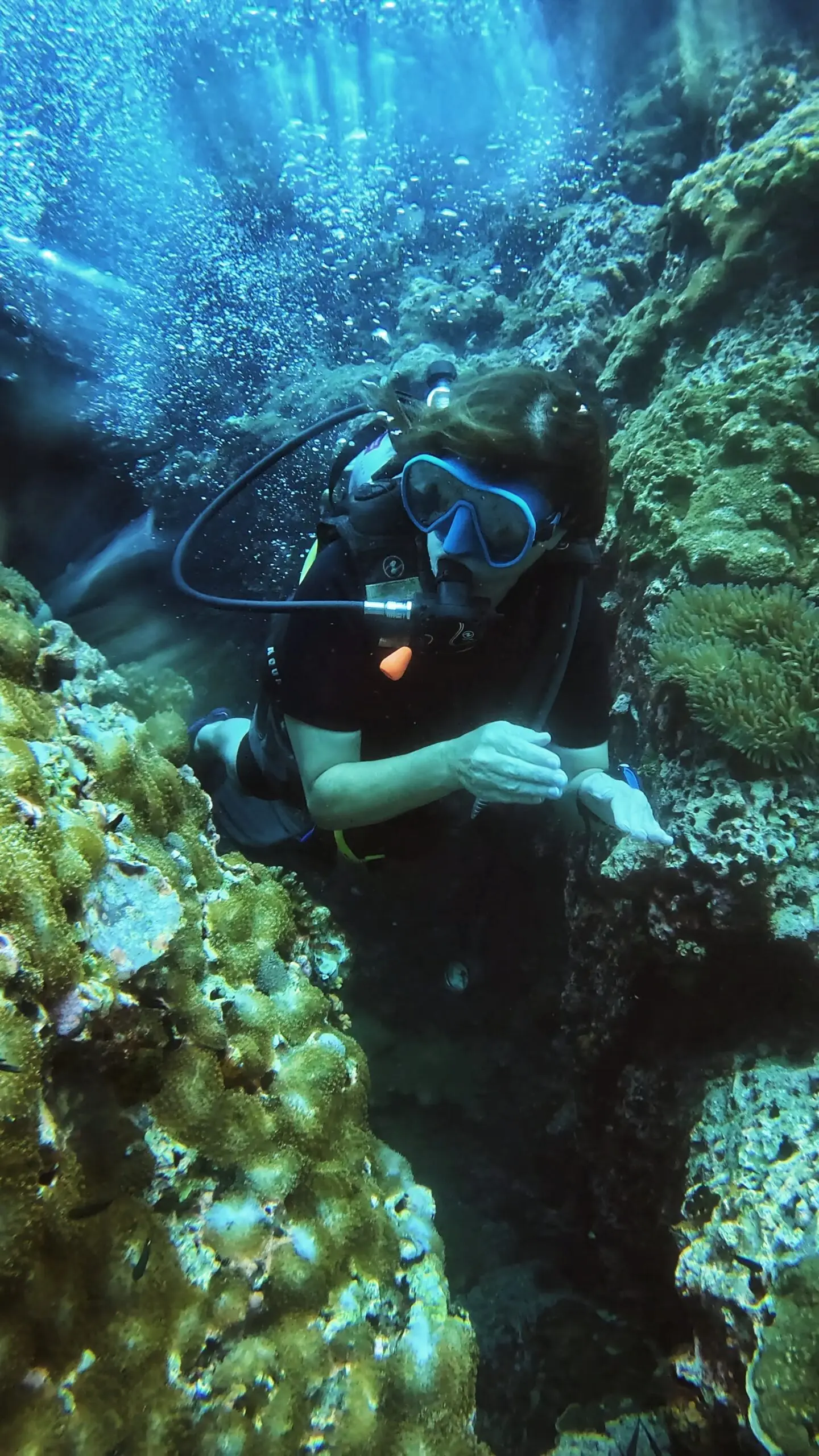 Scuba diver gliding effortlessly through a coral swim-through while practicing perfect buoyancy and underwater control during an SSI Advanced Open Water course at Dive In Koh Tao.