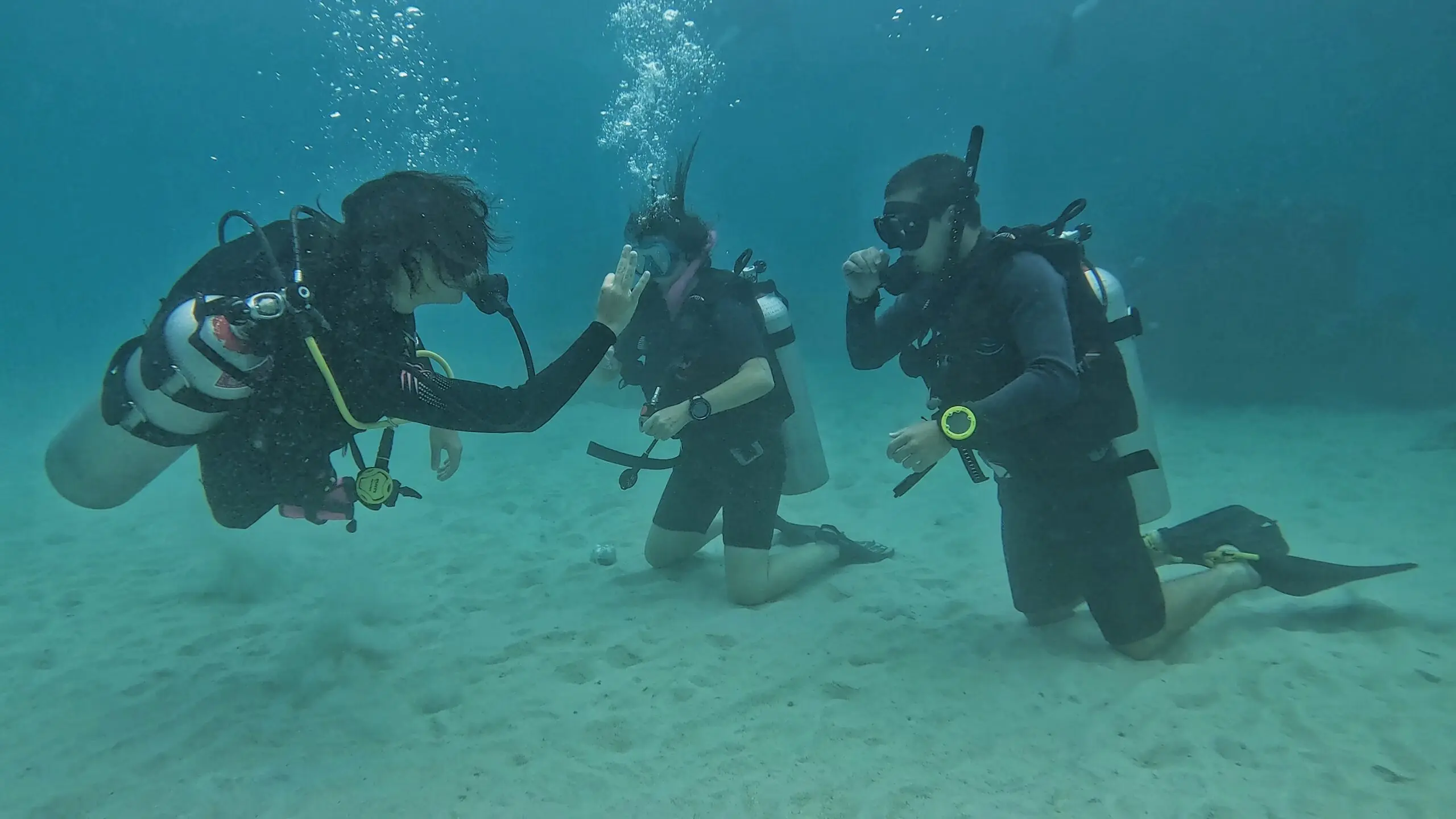 Scuba diving instructor teaching two beginner students underwater during a skills session – personalized Open Water course training at Dive In Koh Tao.