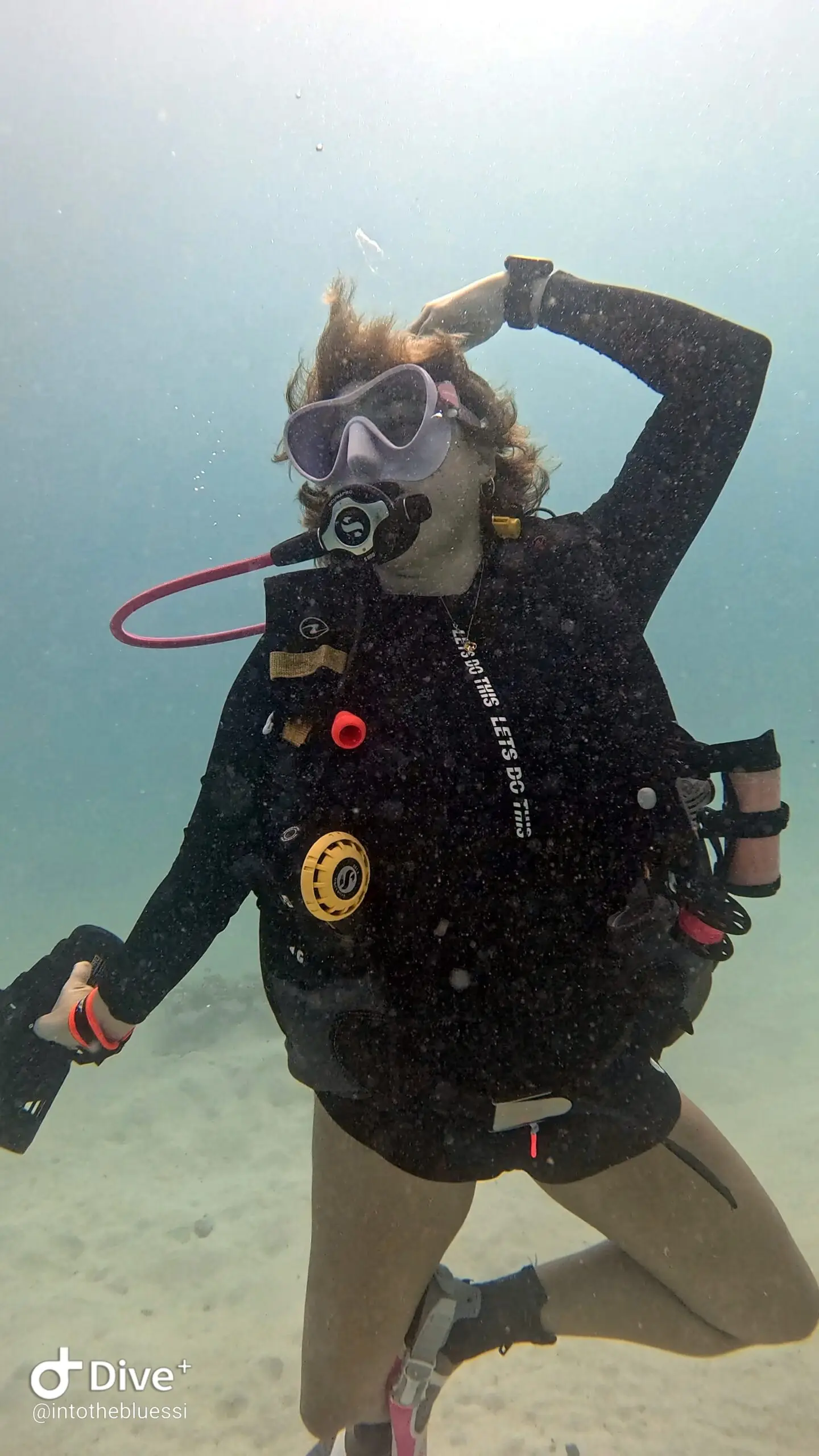 Scuba diver doing a playful ballet pose underwater while holding a DPV (Diver Propulsion Vehicle) during a specialty dive in Koh Tao, Thailand.