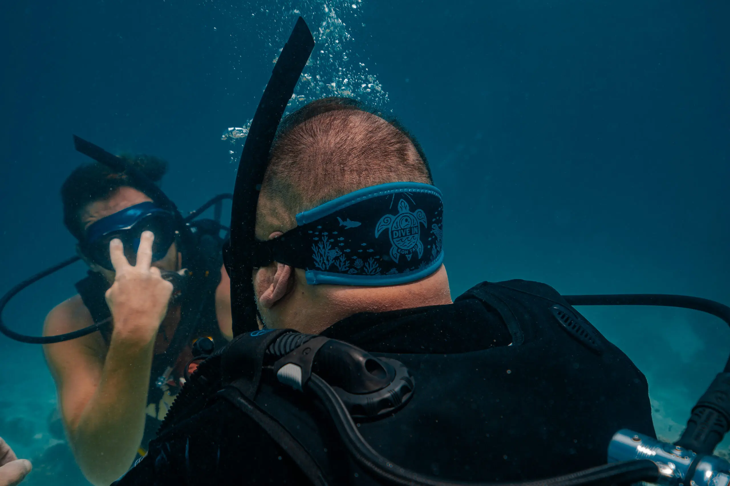 SSI instructor guiding a beginner scuba diver underwater during a Discover Scuba Diving experience in Koh Tao, Thailand.