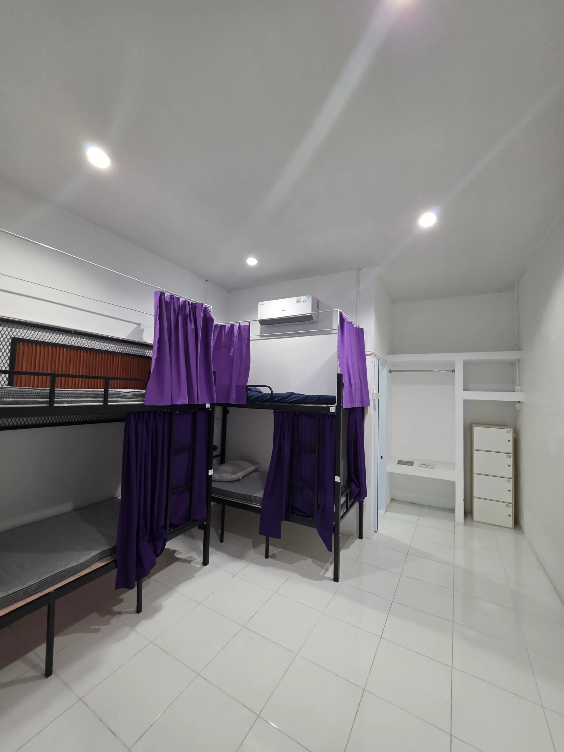 Bunk beds with purple privacy curtains in a clean hostel room in Koh Tao, Thailand