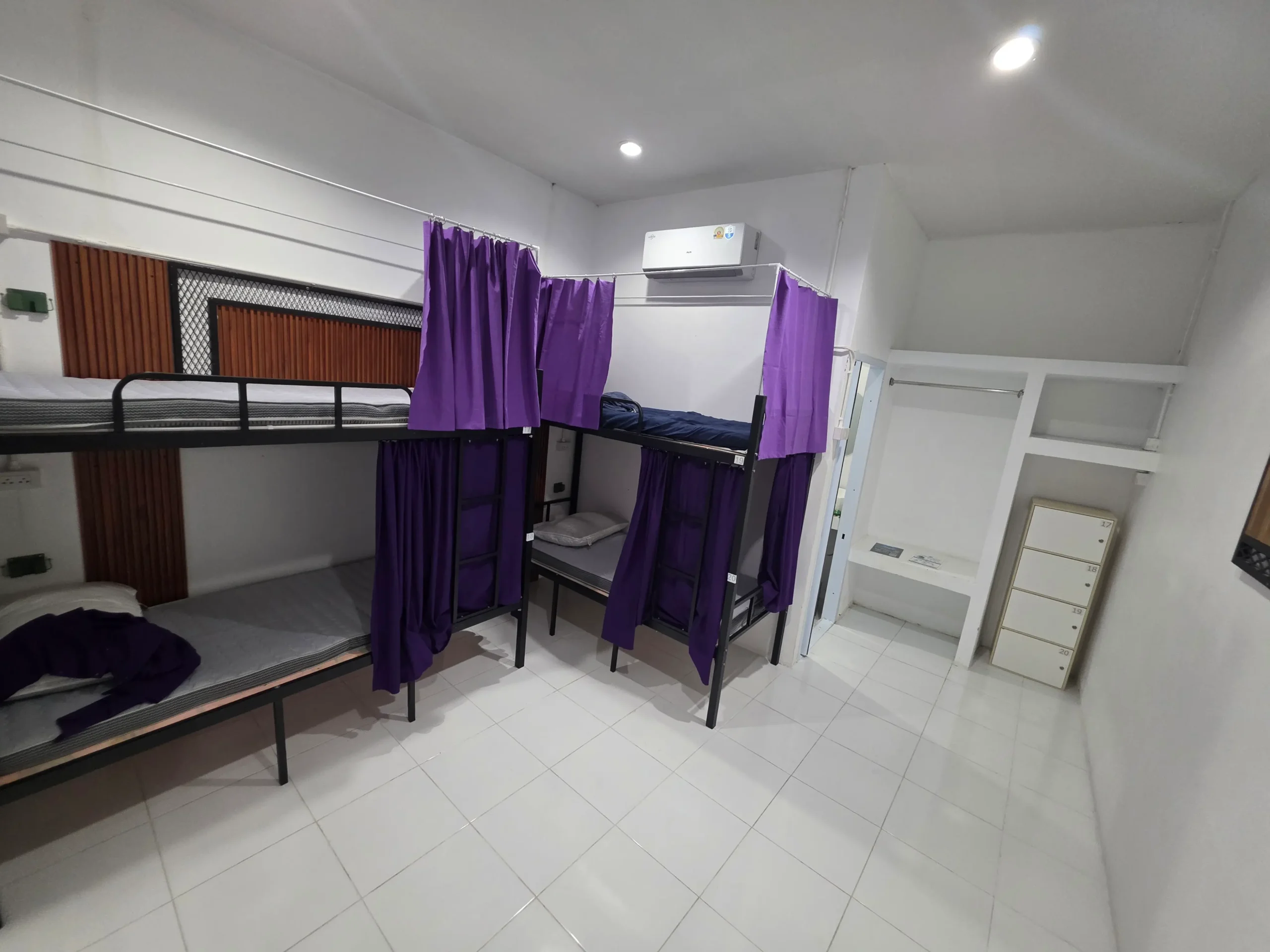 Bunk beds with purple privacy curtains in a hostel room in Koh Tao, Thailand