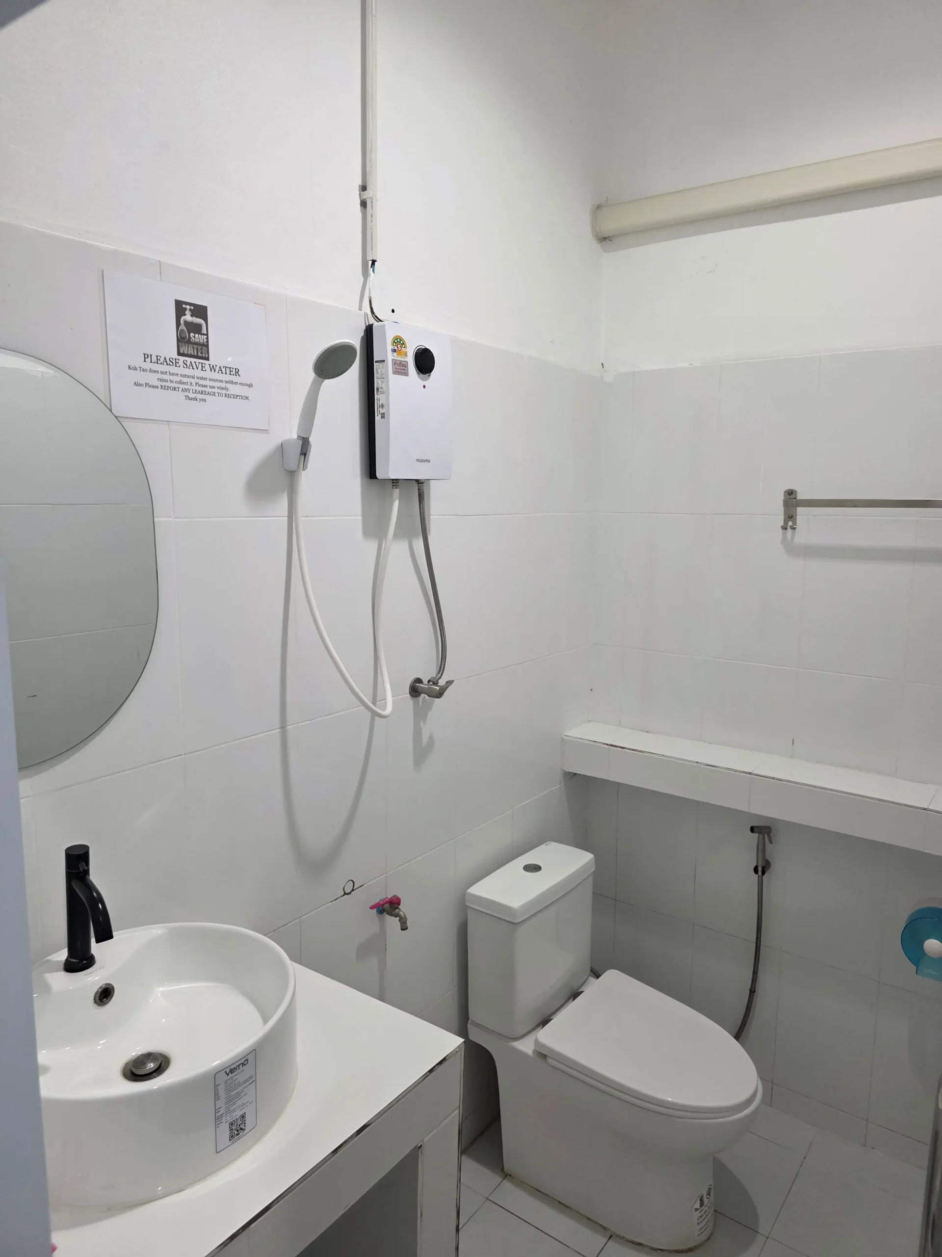 Small clean bathroom with a sink, toilet, handheld shower, and wall-mounted water heater.